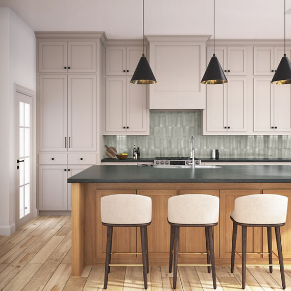 Kitchen with white cabinets, center island, green subway tile on backsplash, and wood floors.