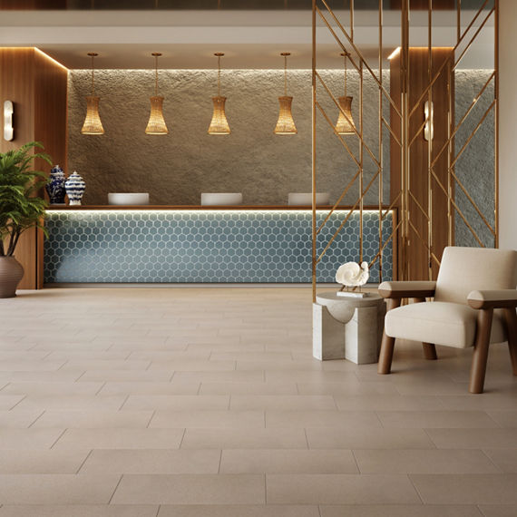 Reception area with blue hexagon mosaic tile on counter, beige stone look rectangle floor tile, white sitting chair, and wood accents.