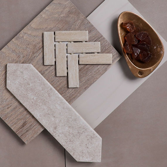 Flatlay with gray concrete look tile, white stone look picket tile, wood tile, white concrete look tile, light beige herringbone mosaic, and a small copper bowl with orange gems in it.