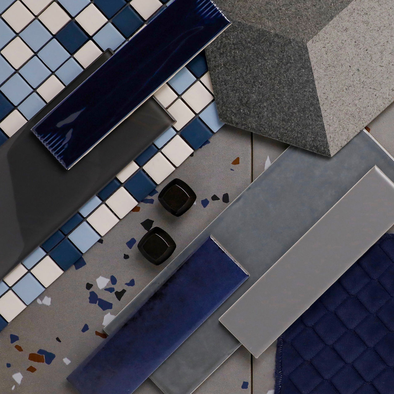 Tile flatlay showcasing blue and gray rectangular tiles, small square mosaic tiles, and geometric patterns in cool tones.