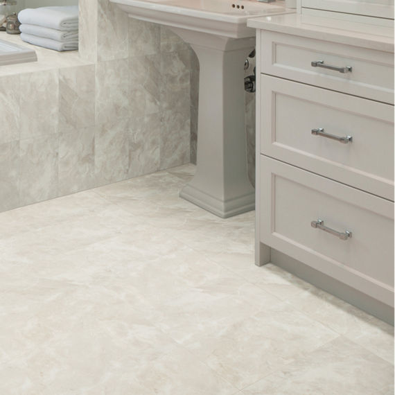 Close up of bathroom with beige marble look rectangle floor tile, light beige cabinets, and beige marble look rectangle tile on walls.