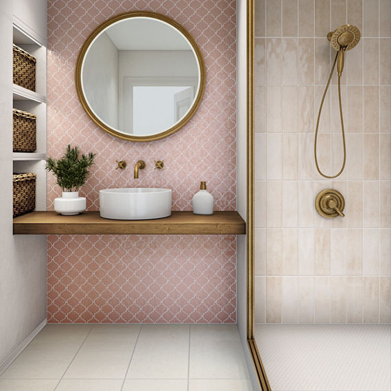 Bathroom with pink arabesque tile on back wall, pink subway tile on shower wall, white concrete rectangle floor tile, wood counter, white sink, and gold accents.