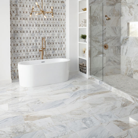 Bathroom with natural stone white marble mosaic on back wall, white marble tile on floor, white marble tile in shower wall, white marble pebble mosaic on shower floor, and gold accents.