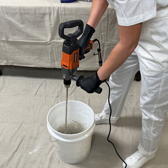 Mixing thinset in bucket with mixing paddle.