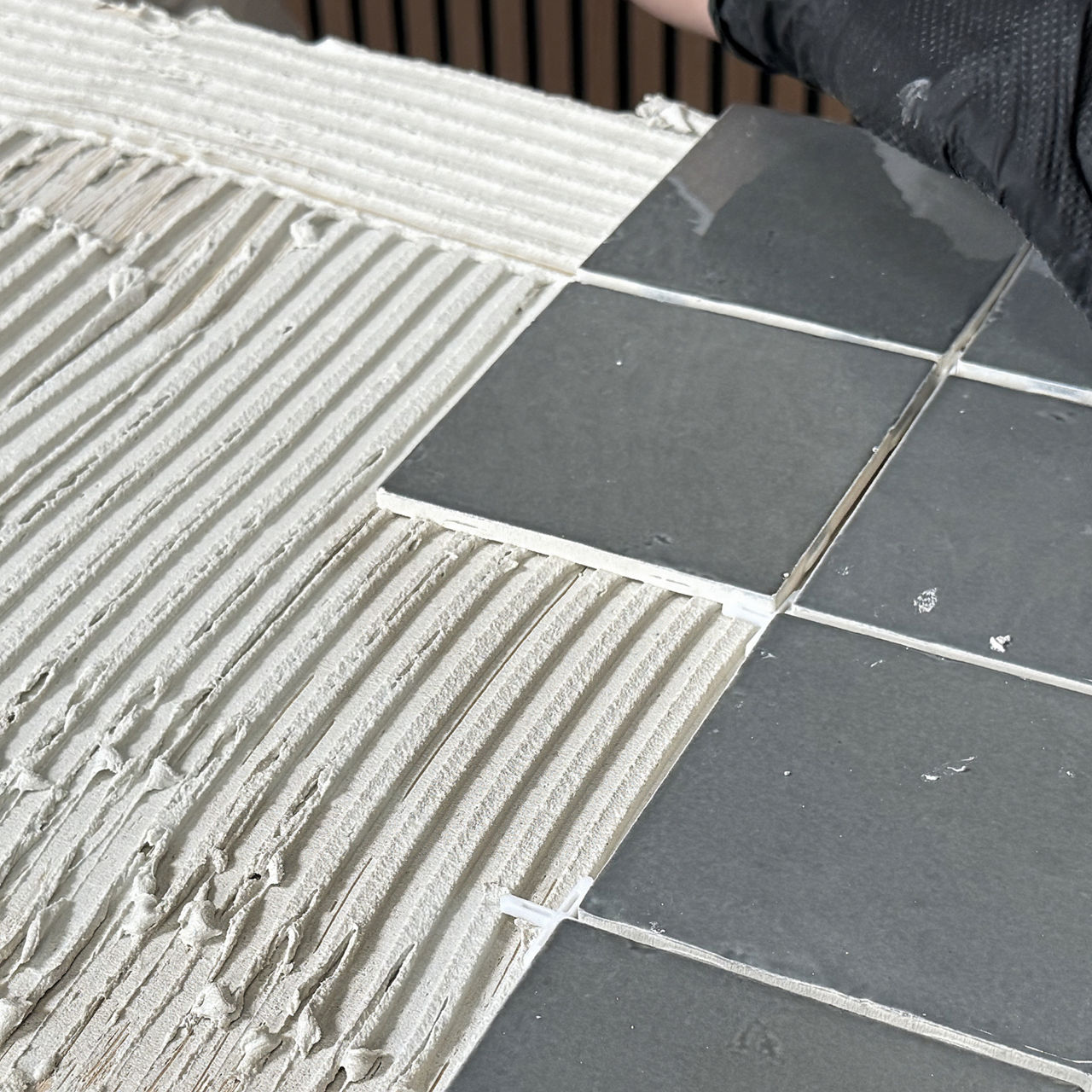Gray square tile placed onto thinset.