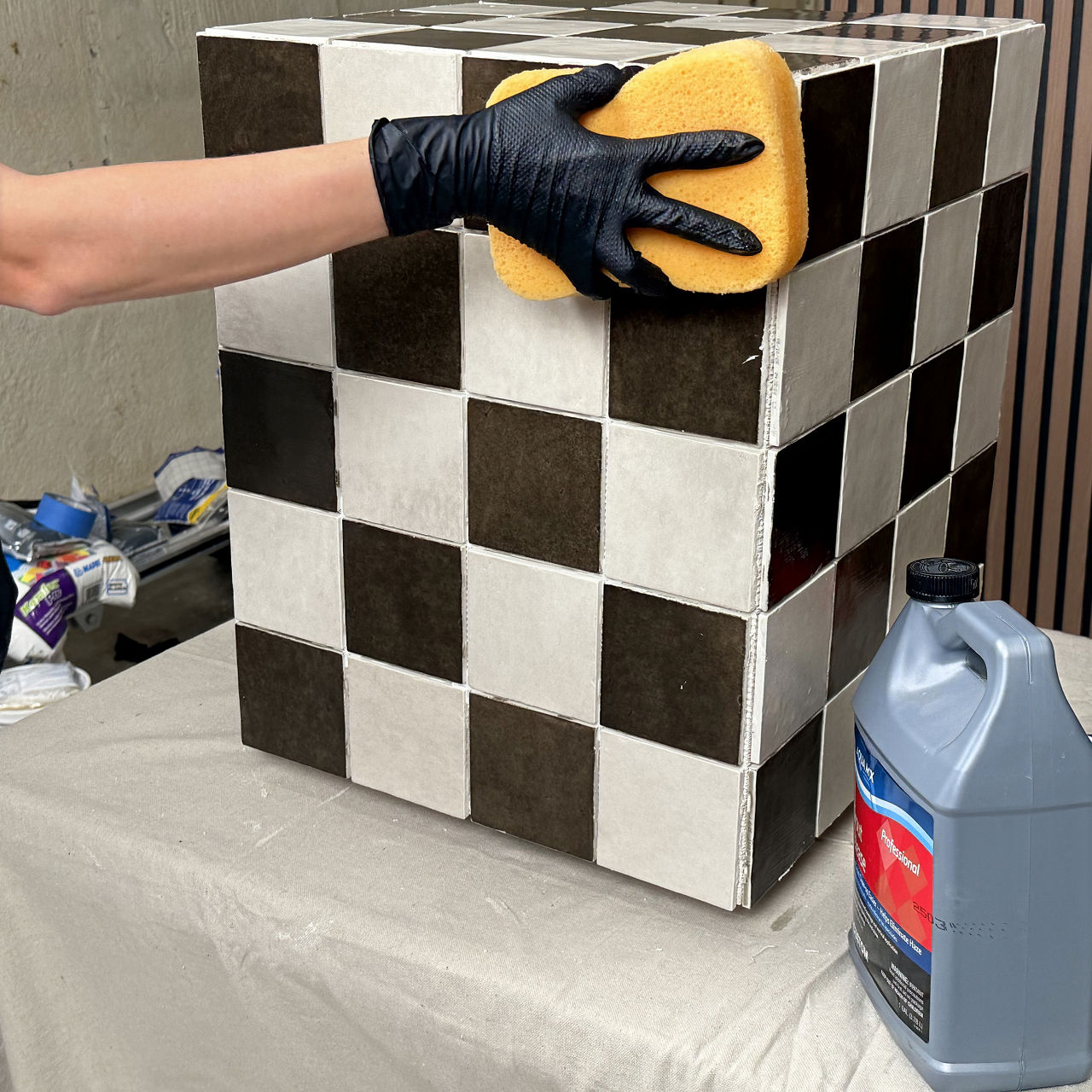 Brown and white square tiled table being cleaned with sponge.