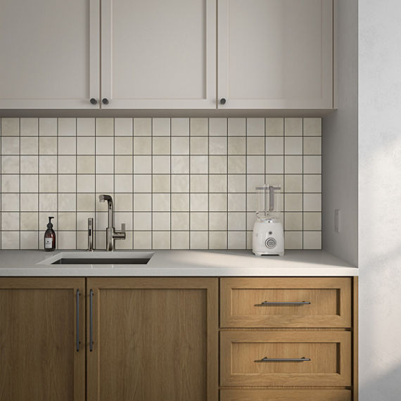 Kitchen with brown and white cabinets, blender on white countertop, and square white wall tile on backsplash.