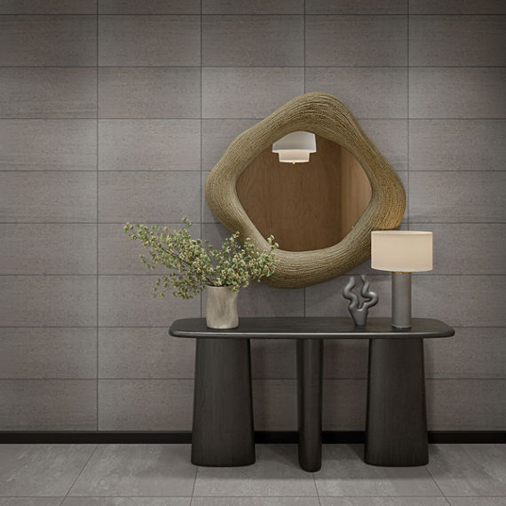 Entry space with black table, wooden mirror above table, vase with greenery, and light gray rectangle concrete look tile on floor and walls.