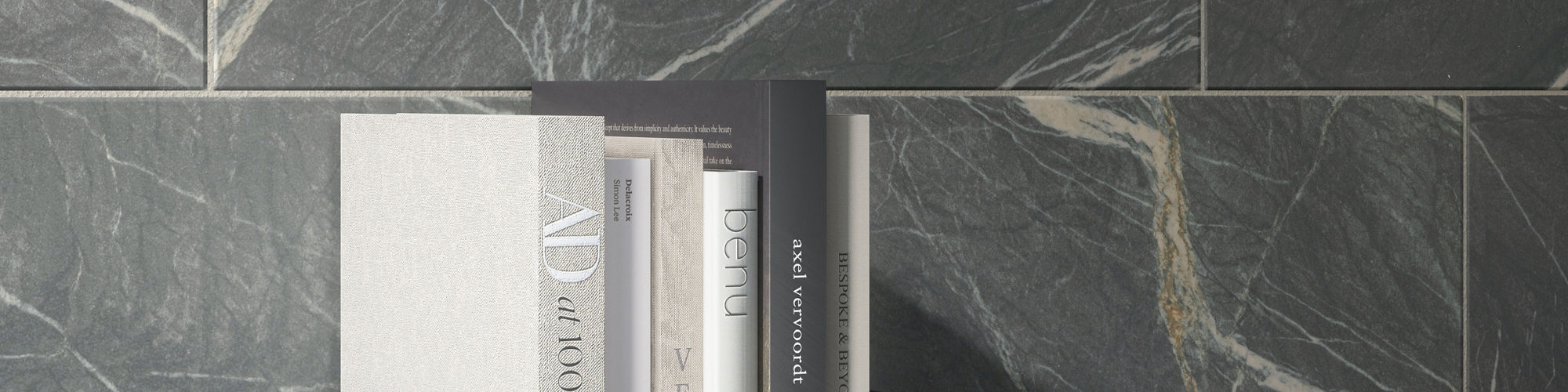 Black stone look rectangle tile on back wall, book stack, and small white tray with candle.