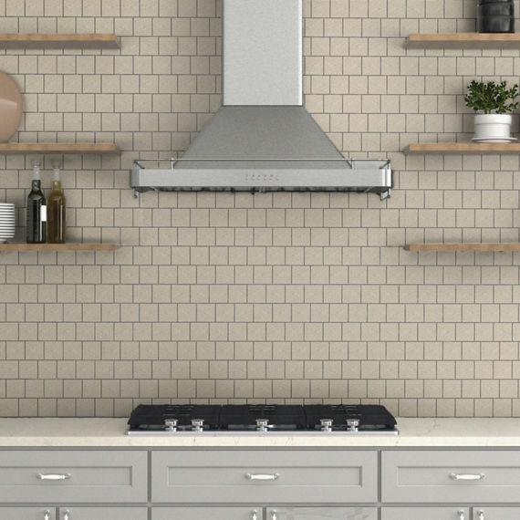 Close up of kitchen with wood floating shelves, gray cabinets, white countertop, and white square mosaic backsplash with black gout.