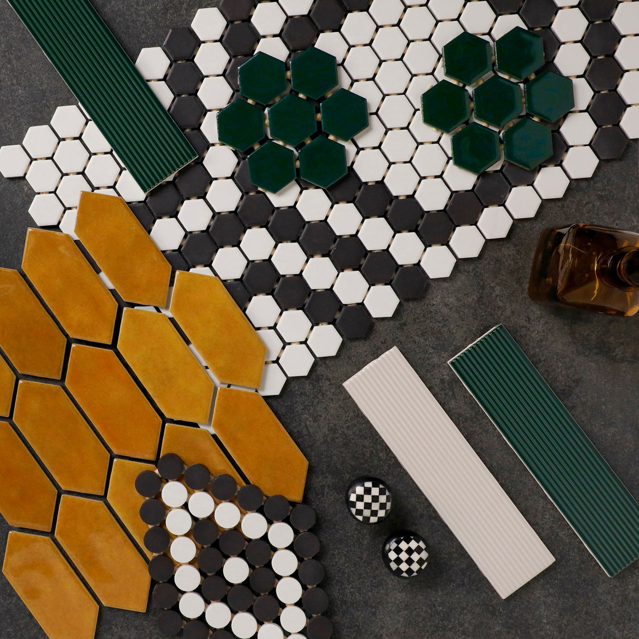 Tile flatlay with mustard yellow hexagon tiles, white round mosaic tiles, and green rectangular tiles arranged in a bold pattern.
