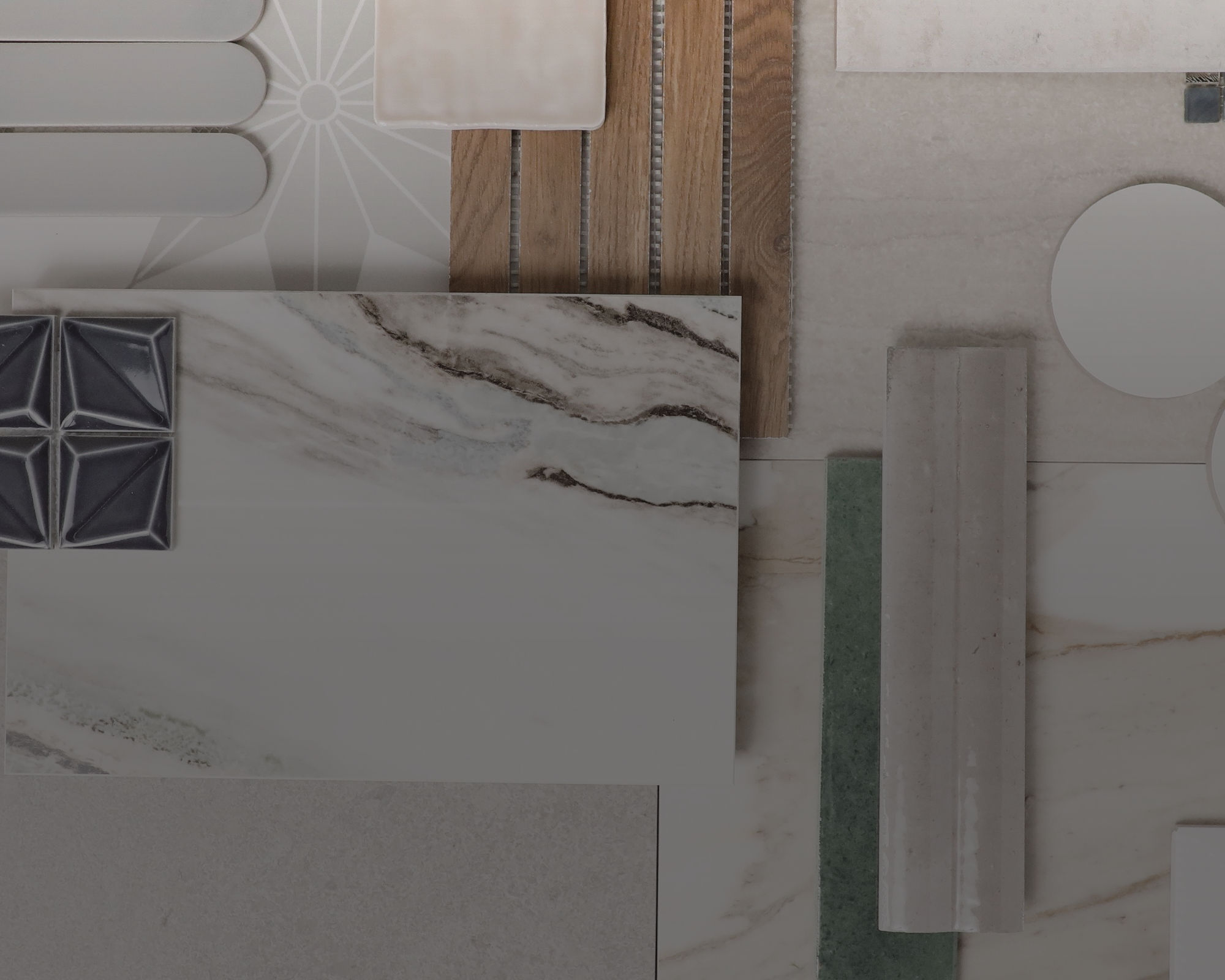 A flat lay arrangement displays various architectural material samples and tiles. Marble, ceramic, wood, and stone pieces are organized in a geometric grid. Shapes include rectangles, circles, rounded strips, and a dark square with raised triangular 