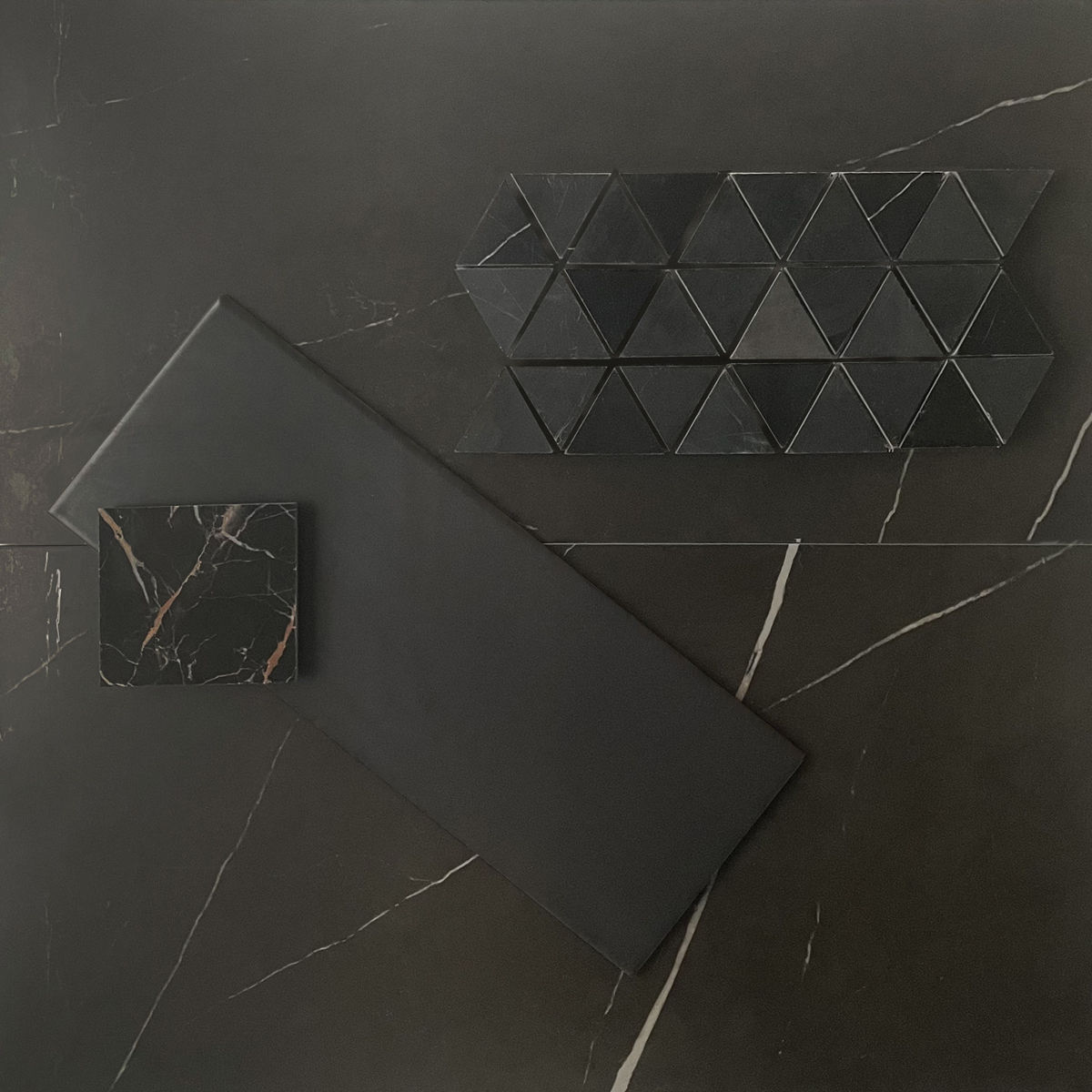 This flatlay contains a marble tile accented by a concrete accent tile, triangle mosaic, and a marble accent tile.