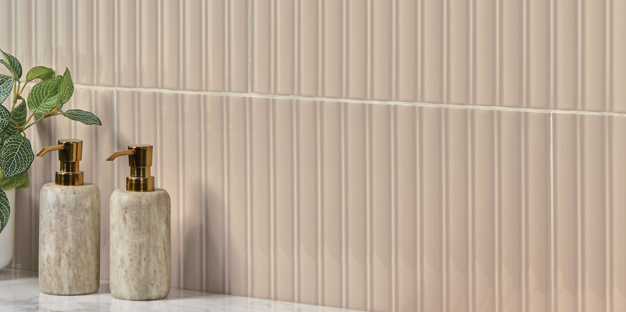 Beige fluted rectangle wall tile, and small bottles of soap.
