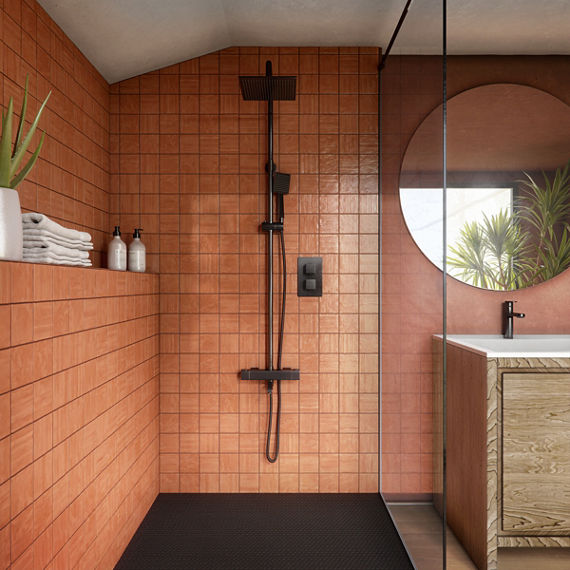 Bathroom with orange square wall tiles with handcrafted look on shower walls, black showerhead, wood sink cabinet, and white countertop on sink.