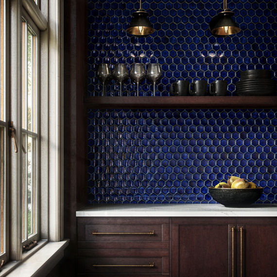 Kitchen with blue hexagon tile on back wall, white countertop, dark wood cabinets, and black bowl of bread.