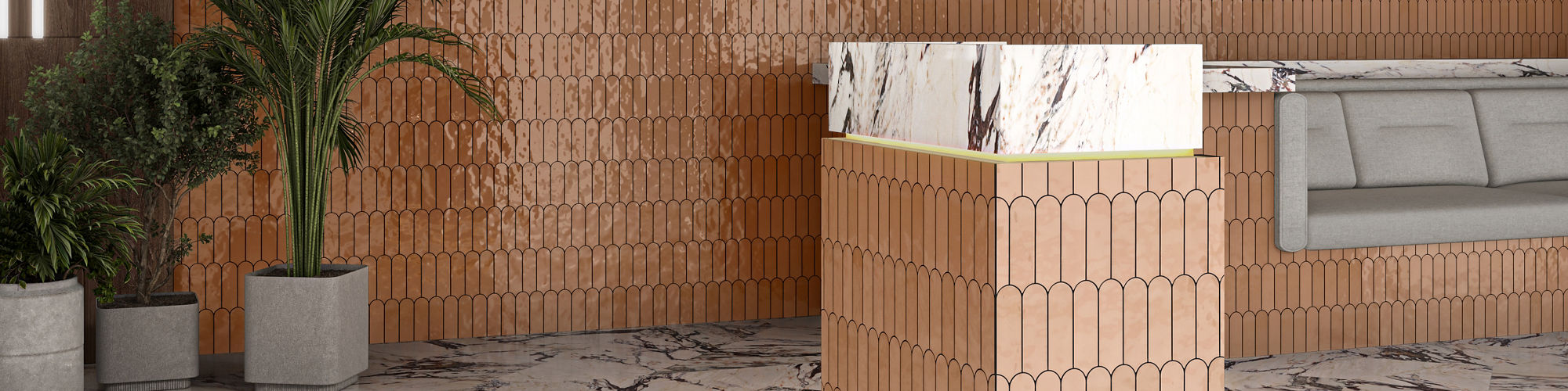 Waiting area with oarnge fishscale mosaic tile on wall and counter, gray couch, and plants.