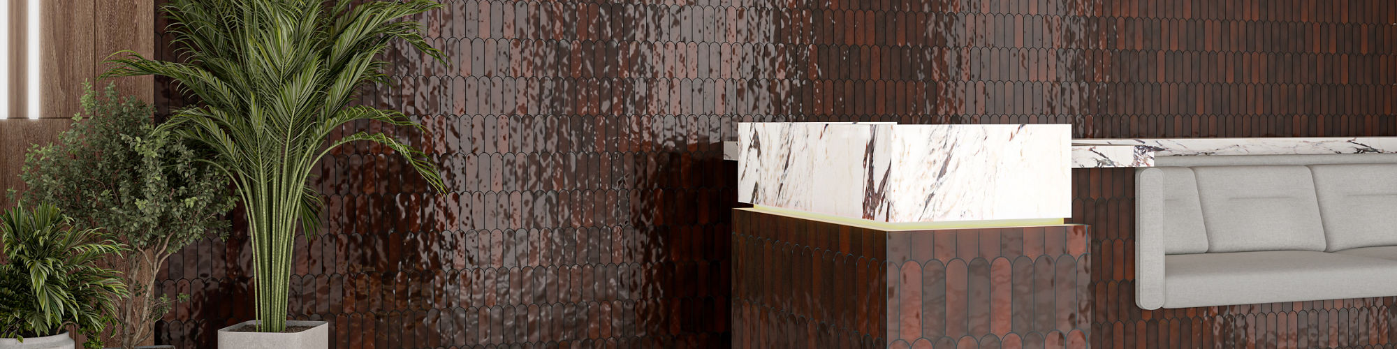 Waiting area with red fishscale mosaic tile on wall and counter, gray couch, and plants.