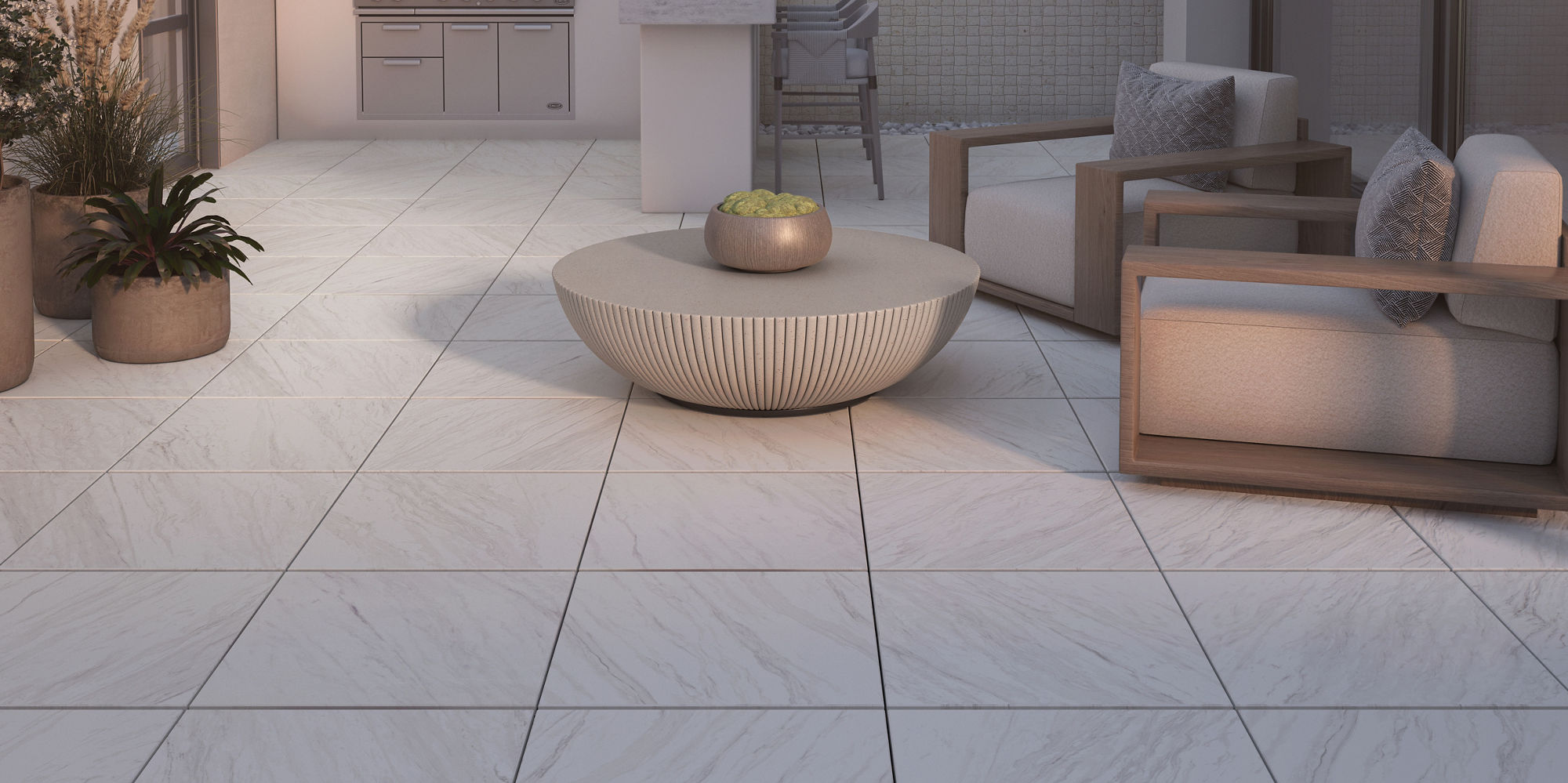 A contemporary rooftop terrace features a sleek outdoor kitchen with a built-in grill and counter space along a tiled wall. Comfortable lounge chairs and a round coffee table with a small plant create a relaxed seating area. Large sliding glass doors