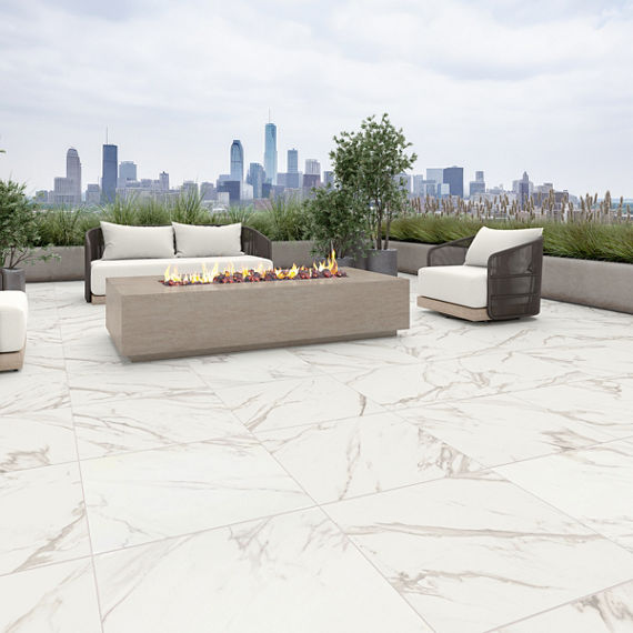 Outdoor patio with marble look square floor tile, white outdoor chairs and couch, and city skyline in the background.