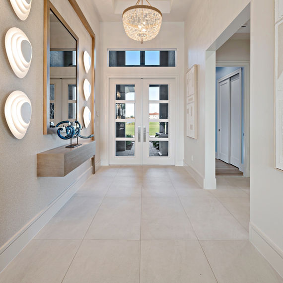 Entry way with light gray rectangle concrete look floor, white walls, and gold accents.