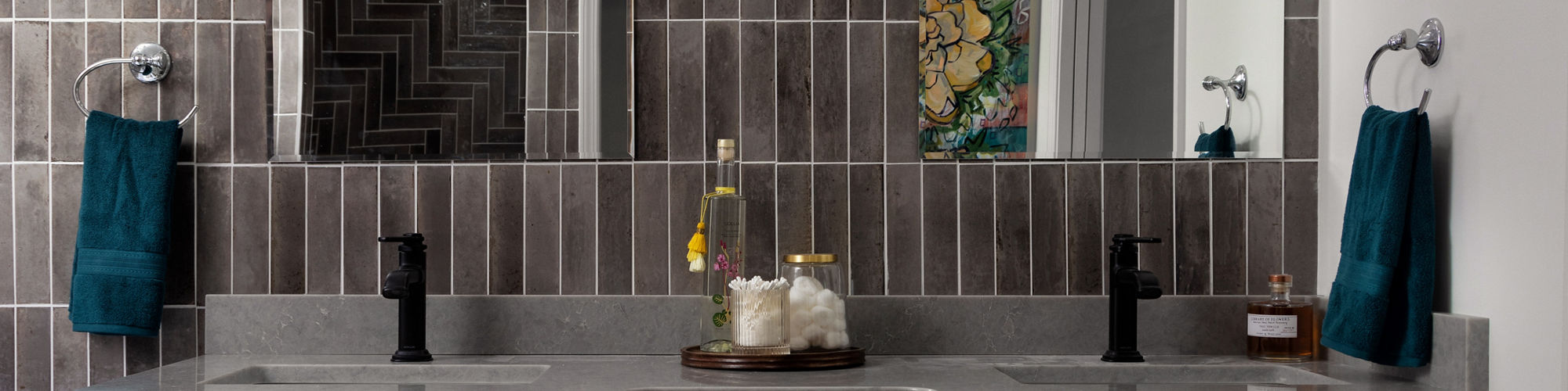 Bathroom with double sinks, white cabinets, black accents, and gray rectangle wall tile.