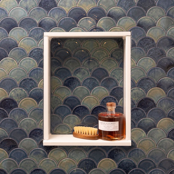 Bathroom shower showing a blue fan mosaic tile on the side wall, a white fan mosaic on the back wall, and a white marble look hexagon mosaic on the shower floor.