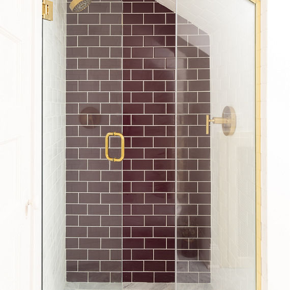 Shower with white marble herringbone mosaic floor tile, white subway tile on the shower walls, and purple subway tile on back shower wall.