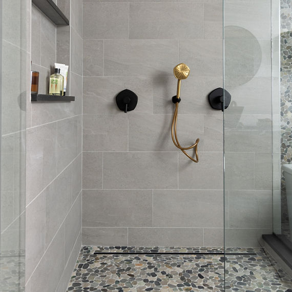 Shower with gray stone look walls and a pebble mosaic floor.