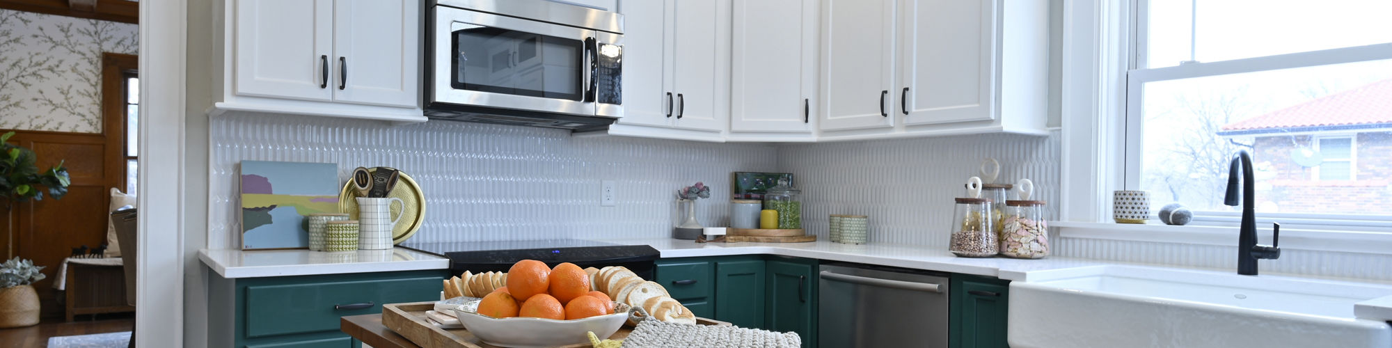 Farm house kitchen with white picket tile backsplash, white quartz countertops, large farm sink, butcher block island, dark green lower and white upper cabinets.
