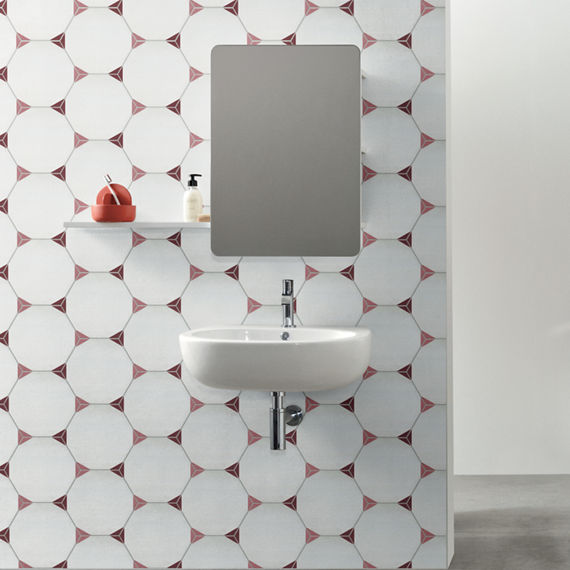 Bathroom with white hexagon tile with pick corners on wall, rectangle mirror, white floating sink, and silver accents.