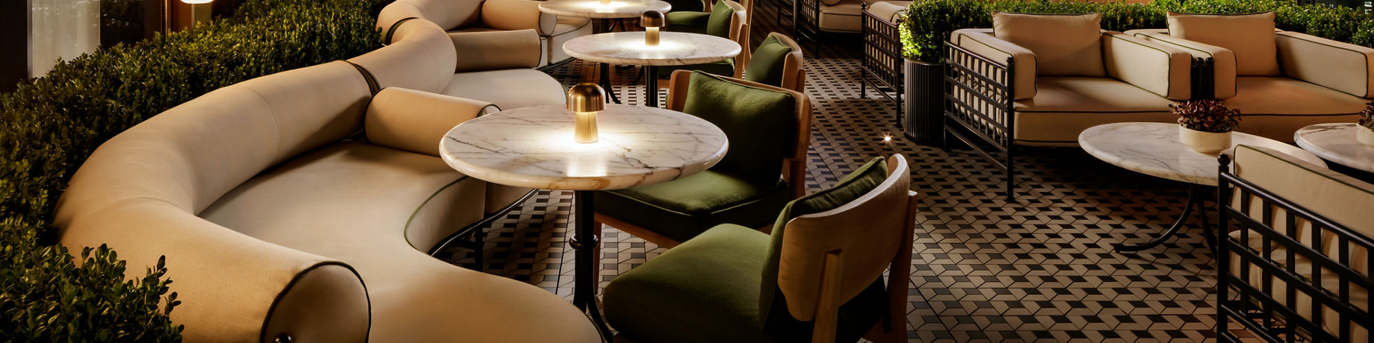 Rooftop restaurant with a white concrete look porcelain slab floor tile custom cut into mosaic, and a black metal look porcelain slab floor tile custom cut into a mosaic, and a concrete look white paver floor tile.