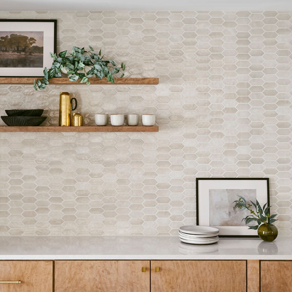 Kitchen with wood cabinets, floating wood shelves, white countertop, and beige capsule mosaic on backsplash.