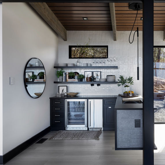 Chip Wades residential renovation, Pinhoti Peak, open kitchen, dining room, living room with black quartz countertops, white glossy wall tile, and floor to ceiling windows.