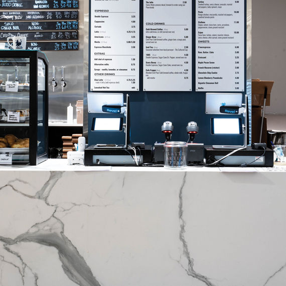 A contemporary coffee shop counter features a large, clearly visible menu board labeled 'CIVIL POUR' above the ordering area.