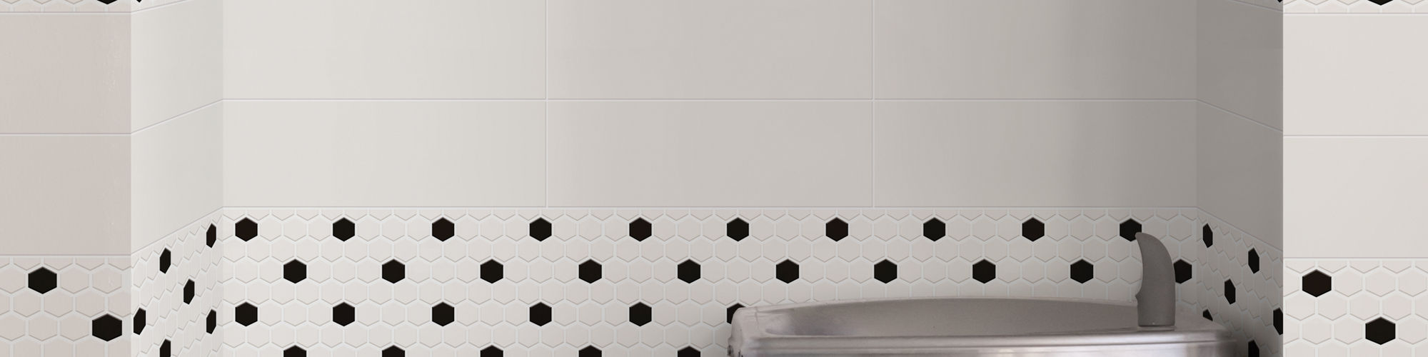 Two water fountains, white rectangle wall tile, white hexagon mosaic, and black hexagon mosaic on back wall.
