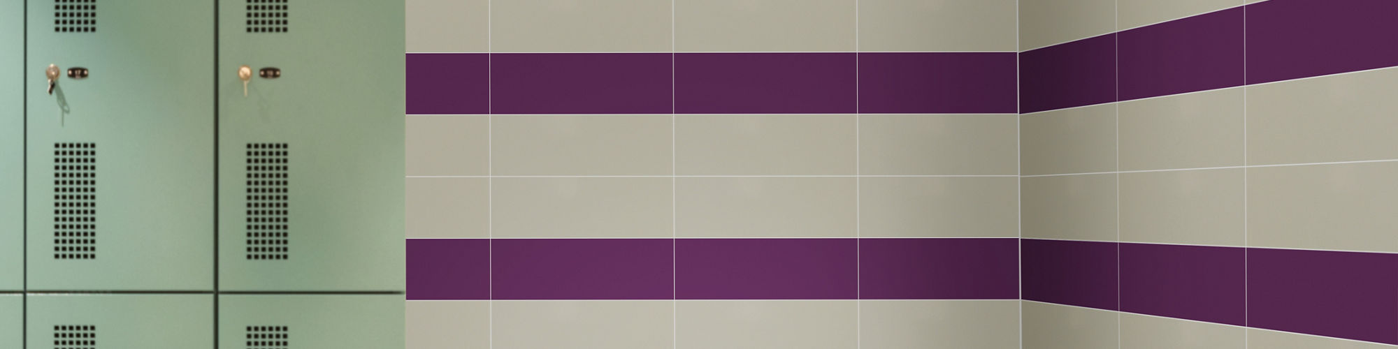 Locker room with gray rectangle wall tile and purple rectangle wall tile forming horizontal line, green lockers, and wooden bench.