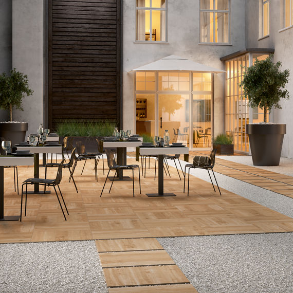 Outdoor sitting area with wood look pavers, outdoor tables and chairs, and gray stone look pavers.