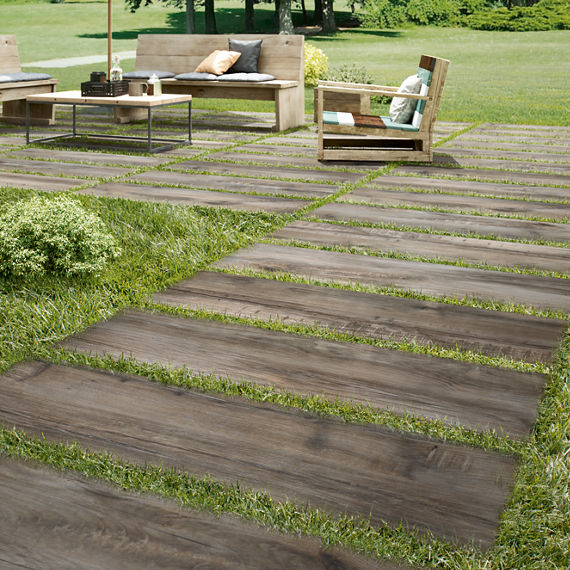 Lawn furniture on 16x48 2 centimeter porcelain pavers that look like seasoned wood, set on top of green grass.