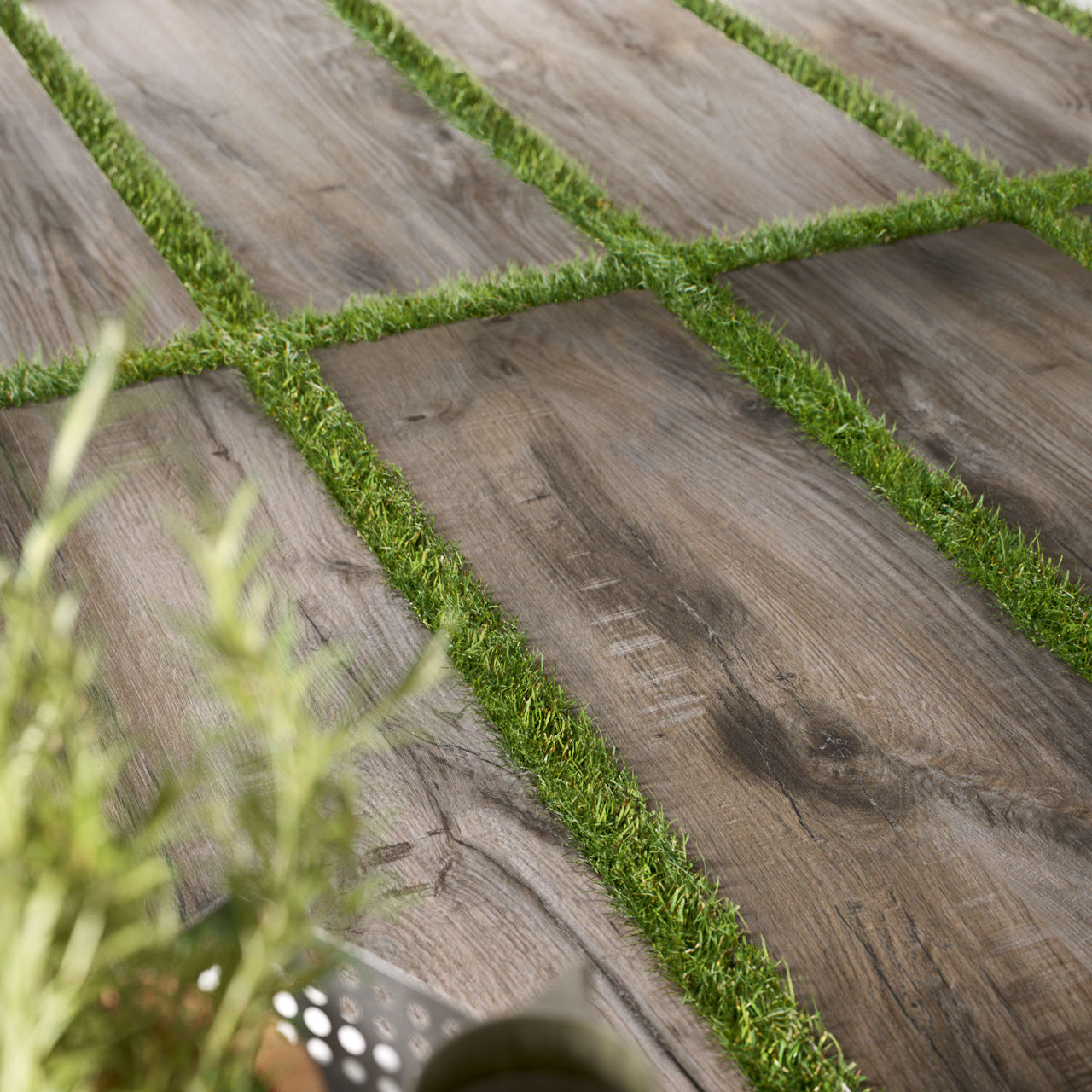 Closeup of a wood look porcelain paver with turf between the tiles with a gardening kit on the side.