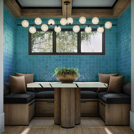 Breakfast nook with light blue square tile on walls, wood bench, black cushions, brown pillows, white marble look table, and wood look floor tile.