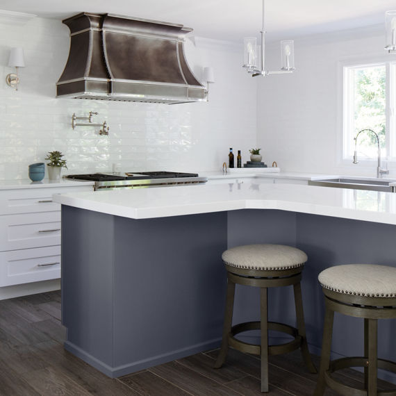 Kitchen with white undulated subway tile on backsplash, white marble look countertop, and two barstools. 