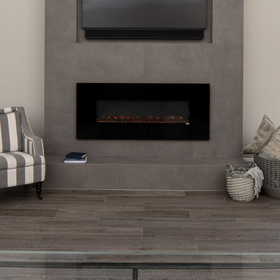 Fireplace with gray porcelain slab surrounding the fireplace, wood floors, and two striped sitting chairs.