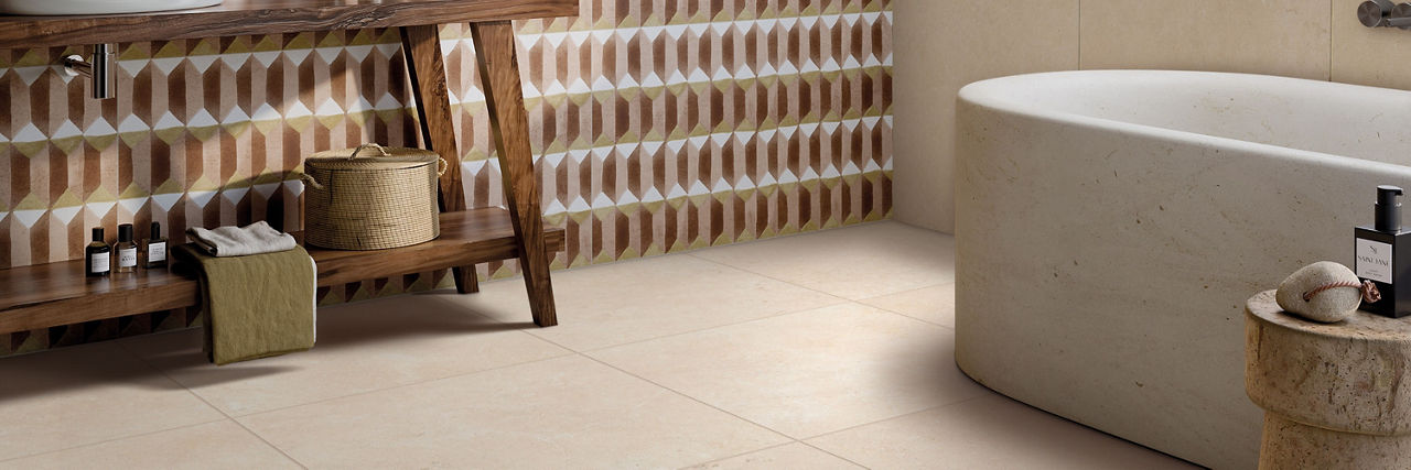 Bathroom with terracotta, peach, and white decorative wall tile, beige limestone stone look floor tile, soaker tub, open shelf wood vanity.