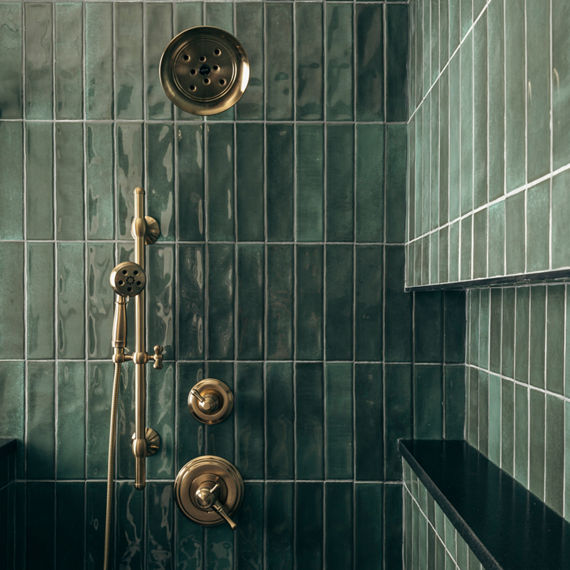 Shower with green subway tile on shower walls, and silver accents.
