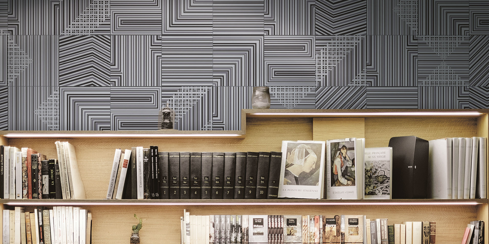 Metallic-look, geometric pattern tile on a library wall.Light wood bookshelves with books and arm chair in the foreground.