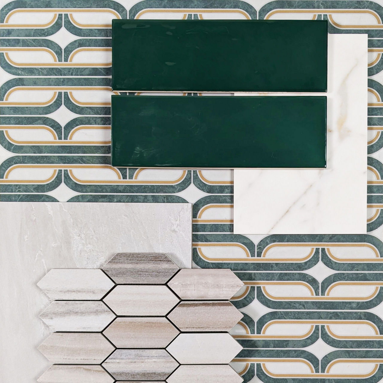 A collection of decorative tile samples is arranged on a patterned surface. Two dark green rectangular tiles sit beside a white marble-look tile. Below them, a cluster of elongated hexagon tiles in neutral tones is displayed. The background features 