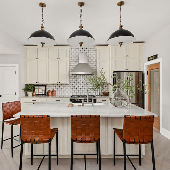 Kitchen with white and glass petal shaped mosaic backsplash, white quartz countertop, and white cabinets.