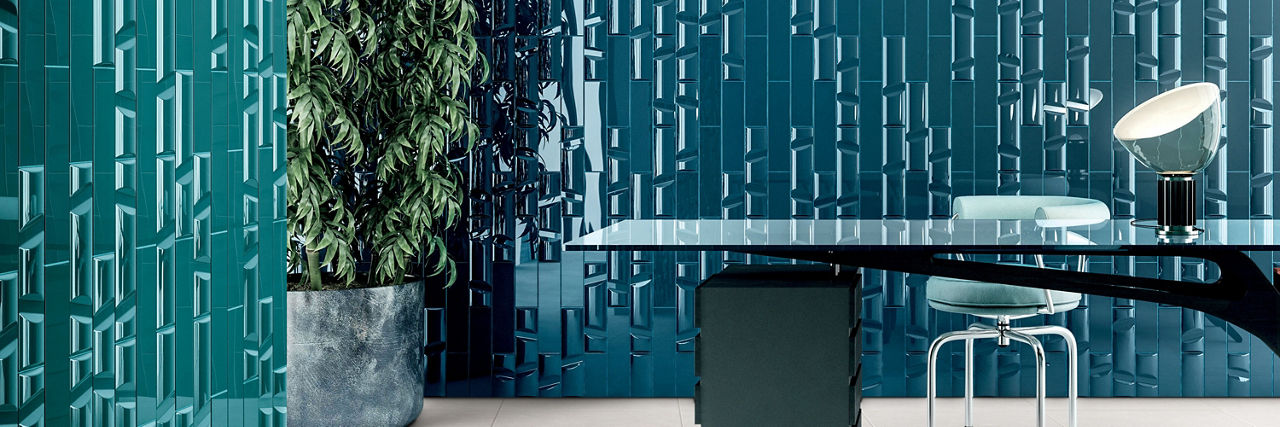 Home office with green glossy dimensional tile wall and teal glossy dimensional tile wall, glass top desk with metal base and white leather chair.