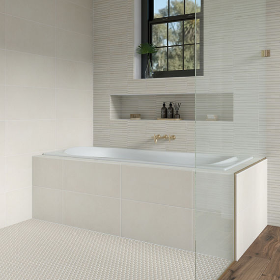 Bathroom with white concrete look rectangle tile on bathtub surround, white textured wall tile, white mosaic on shower floor, wood floor tile, and gold accents.